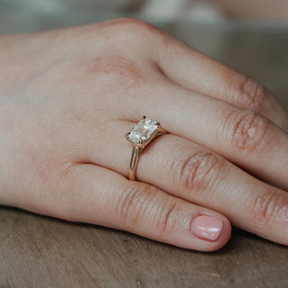 Lab grown diamond engagement ring with an east-west old mine cut center worn on the hand, cathedral shank in yellow gold.