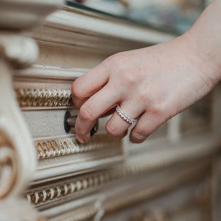 Oval cut lab diamond band worn on the hand reaching toward carved woodwork, yellow gold profile in soft light.