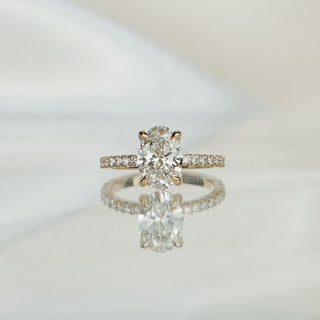 Yellow gold engagement ring with a 2.00 carat oval lab diamond over a hidden halo, pavé stones along the band.