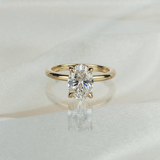 Yellow gold solitaire with a 2.01 carat oval lab diamond, eighteen concealed round brilliants circling beneath the basket.