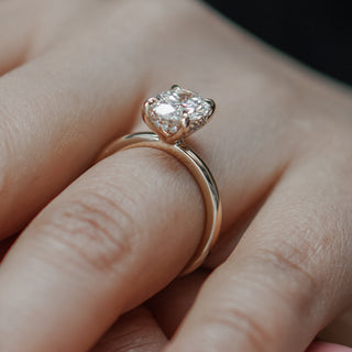 Lab grown diamond oval solitaire worn on the hand, hidden halo adding spread beneath the four prongs.
