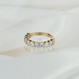 Lab grown diamond oval cut wedding band in yellow gold on satin fabric, eleven ovals in shared prongs across the front.