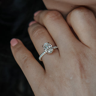 Close-up of a hand wearing an oval diamond ring next to hair.