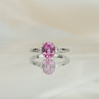 White gold three-stone engagement ring with a 1.66 carat oval pink Sapphire and pear shape Diamond sides.