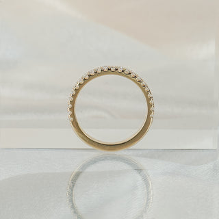 Micro pavé half eternity band standing upright with reflection, yellow gold circle with stones across the face.