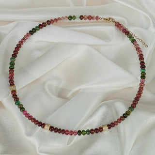 Full circle view of a multi-color Tourmaline bead necklace on satin, continuous strand of oval beads in pink and green.