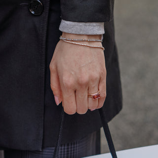 Hand wearing a ring with a pink tourmaline, holding a bag.