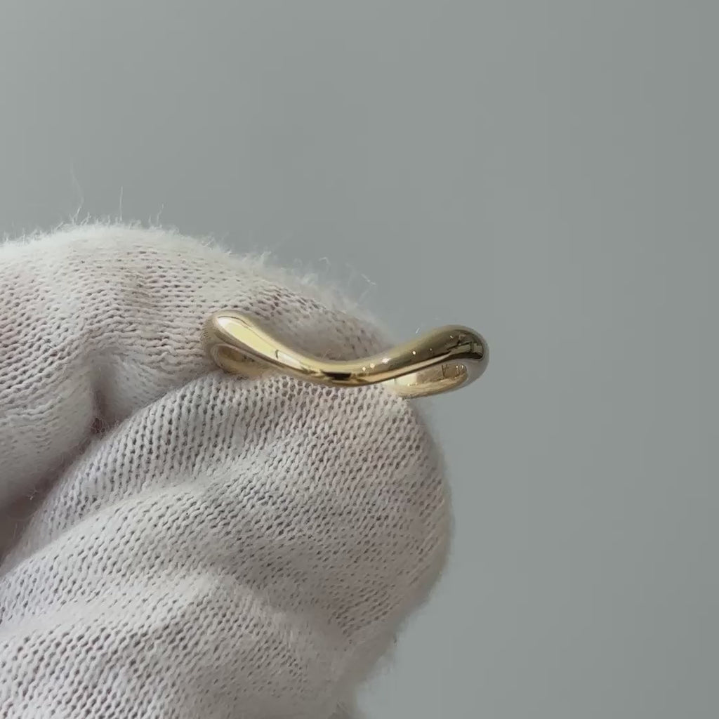 Video of a yellow gold shadow wedding band on a gloved hand, tapered curve catching light as it turns.