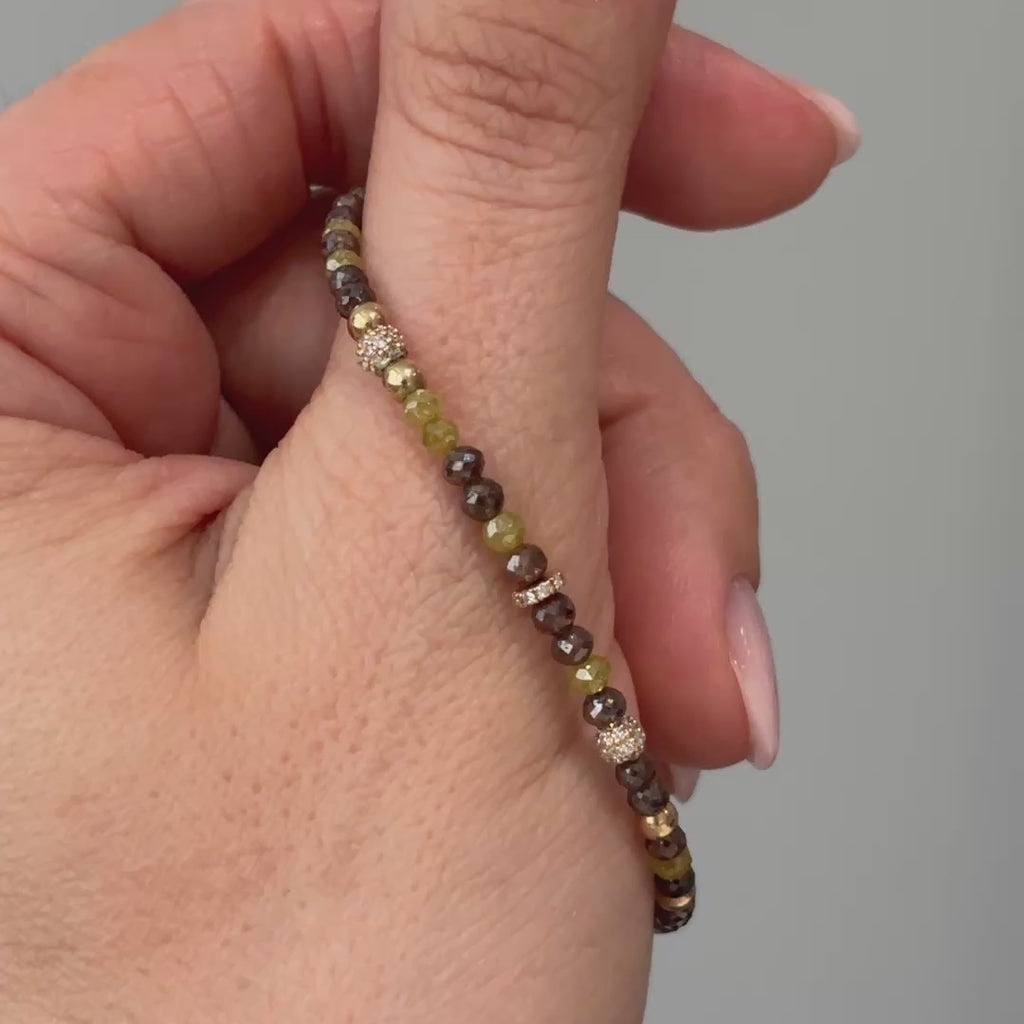 Video of a natural yellow and brown raw faceted Diamond bracelet held between fingers, stone color variation in motion.
