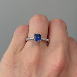 Video of a white gold cushion cut blue Sapphire engagement ring worn on the hand, deep blue center catching light in motion.