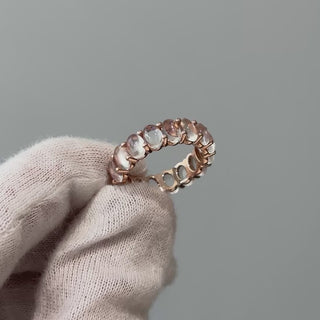 Video of a rose gold natural Moonstone full eternity ring on a gloved hand, adularescence shifting across the stones in motion.