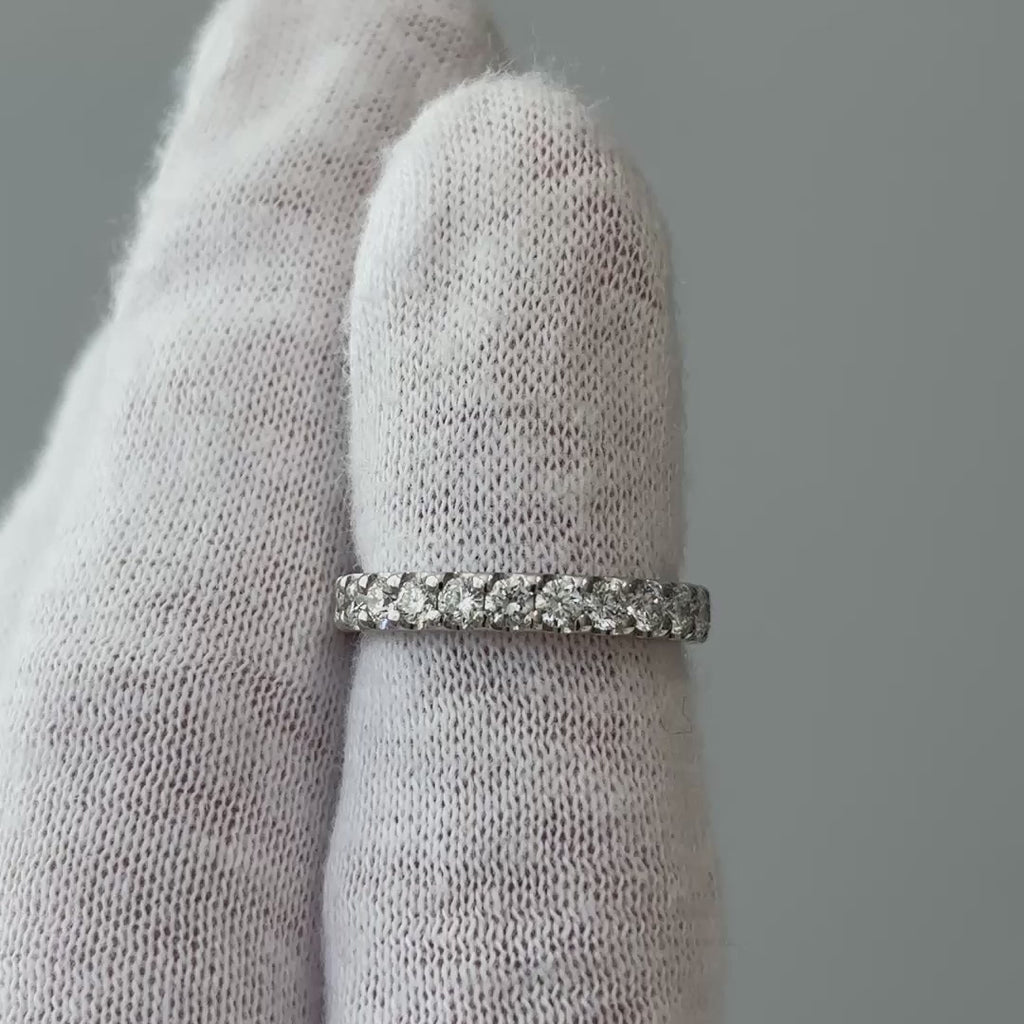 Video of a white gold lab grown diamond full eternity band on a gloved finger, uninterrupted stone line turning through the light.