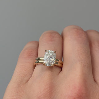 Video of a yellow gold cushion cut lab grown diamond double shank solitaire worn on the hand, stacked bands turning through the light.