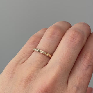 Video of a 14k yellow gold faceted wedding band worn on the hand, flat panels shifting light as the hand moves.

