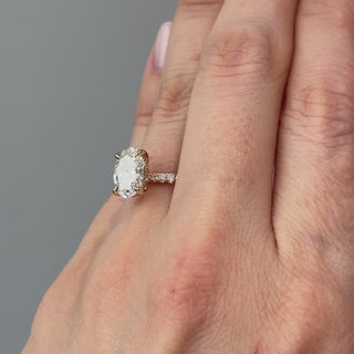 Video of a yellow gold oval lab grown diamond hidden halo engagement ring worn on the hand, light running the pavé shank in motion.