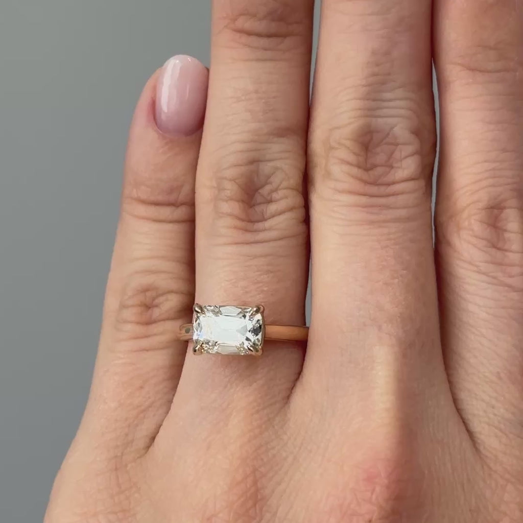Video of a yellow gold east-west old mine cut lab grown diamond solitaire worn on the hand, elongated antique style facets in motion.