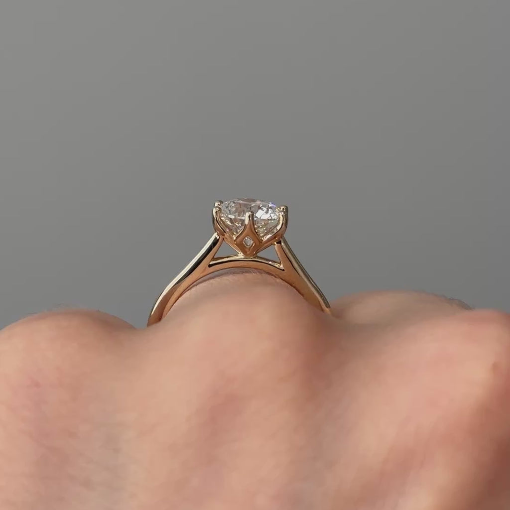Video of a yellow gold round brilliant lab grown diamond flower head solitaire worn on the hand, elevated crown turning through the light.