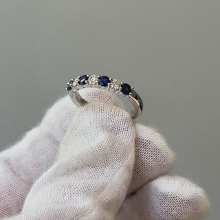 Video of a platinum natural Ceylon blue Sapphire and Diamond band on a gloved hand, blue and white stones turning through the light.