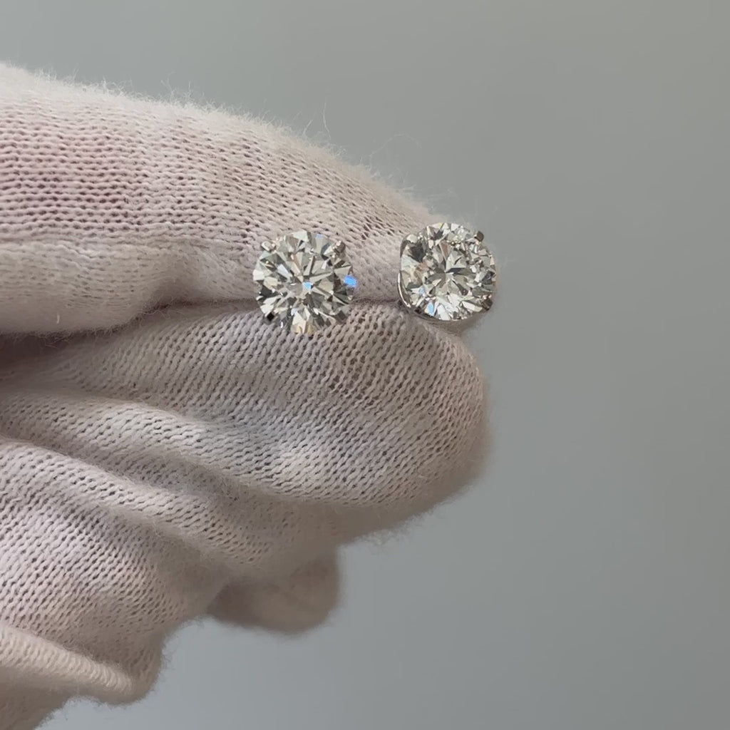 Video of lab grown diamond round brilliant studs held on a gloved hand, stones showing brilliance in motion.