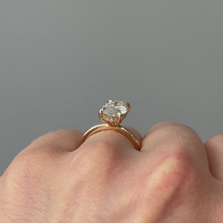 Video of a yellow gold oval lab grown diamond hidden halo solitaire worn on the hand, brilliance spreading from beneath the stone in motion.