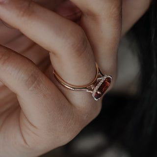 Pink Tourmaline solitaire worn on the hand, radiant cut stone with a hidden halo beneath in yellow gold.