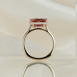 Radiant cut pink Tourmaline engagement ring standing upright with reflection, slim yellow gold band rising to the hidden halo.
