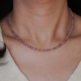 Sapphire tire bead necklace in natural multi-color worn at the neckline, 16 inch length sitting at the collarbone.