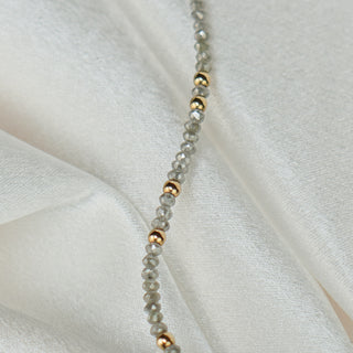 Close view of raw faceted grey Diamonds with a 14k gold bead along the bracelet strand.