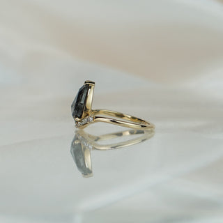 Side view of a salt and pepper pear engagement ring, rose cut dome and slim yellow gold shank visible.