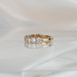 Side view of a lab diamond scallop shared claw band in yellow gold, large stones tapering to a plain back.