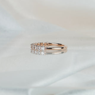 Side view of a lab grown diamond shared prong band in rose gold, stone row tapering to a plain back.