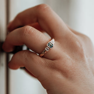 Teal sapphire engagement ring on hand opening knob.