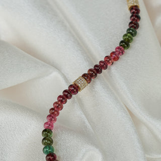 Close view of natural Tourmaline oval beads with a 14k yellow gold and diamond spacer along the strand.
