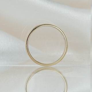 Half-round yellow gold wedding band standing upright, domed 4.1mm profile visible against a soft neutral backdrop.