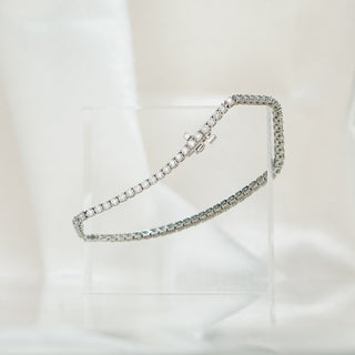 Natural Diamond tennis bracelet in white gold on an acrylic block against soft white fabric.