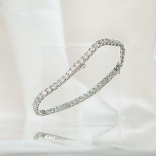 White gold lab diamond tennis bracelet on an acrylic block, continuous line of round brilliant stones.