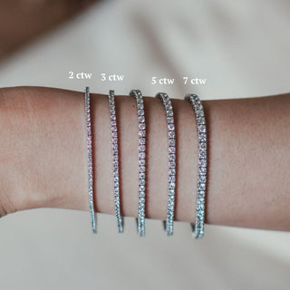 Four widths of white gold natural Diamond tennis bracelets worn on the wrist, size comparison from 2 to 5 ctw.