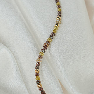 Close view of raw faceted Diamonds in yellow and brown along the bracelet strand, unpolished facets in warm tones.