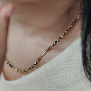 Close-up of a beaded necklace on a person wearing a white top.
