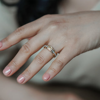 Close-up of a hand wearing a gold ring with a yellow diamond.