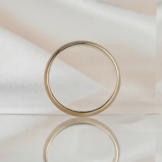 Half-round yellow gold wedding band standing upright, showing the 4.1mm width and rounded profile against a soft neutral backdrop.